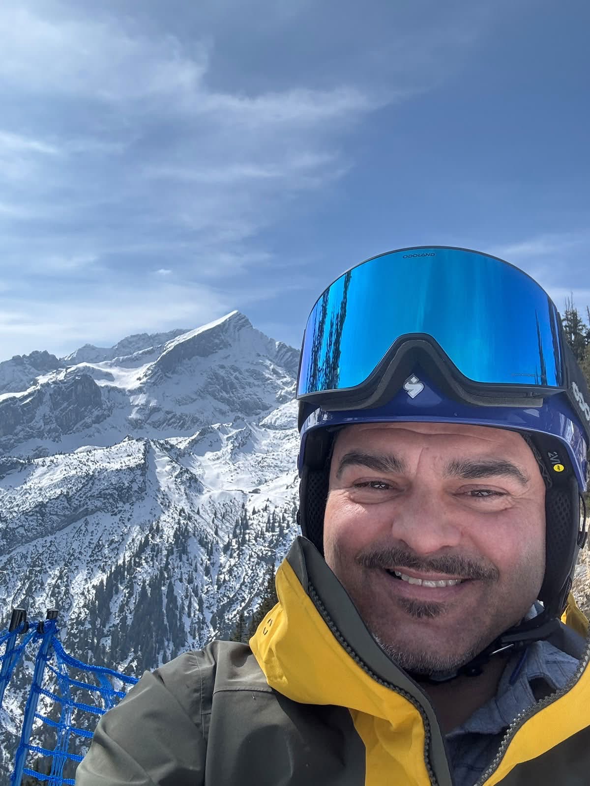 Alberto mit Skihelm und Skibrille vor schneebedeckter Bergkulisse
